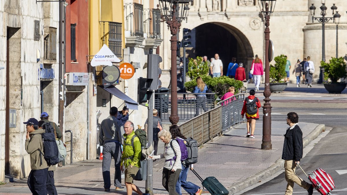 Turistas con maletas en la plaza de Vega, en las cercanías de la estación de autobuses y el Arco de Santa María y la Catedral.
