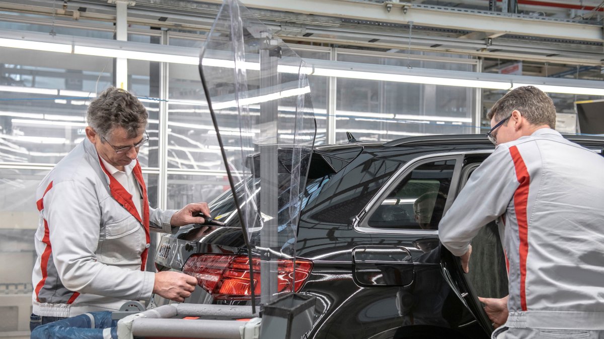 Archivo - Dos trabajadores produciendo un coche en una planta de Audi.