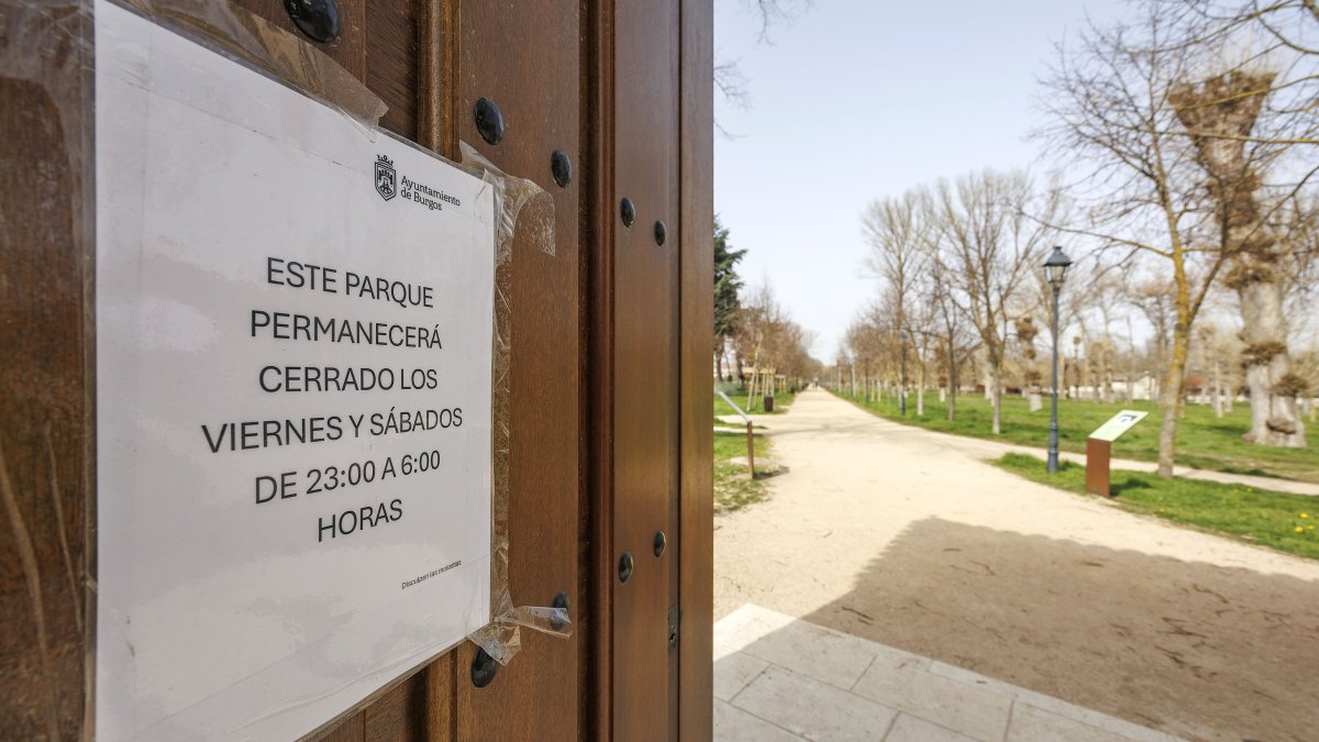 Cartel en una de las puertas de acceso al parque de El Parral, en el que se advierte de que se cierran en la noche de viernes y sábados.
