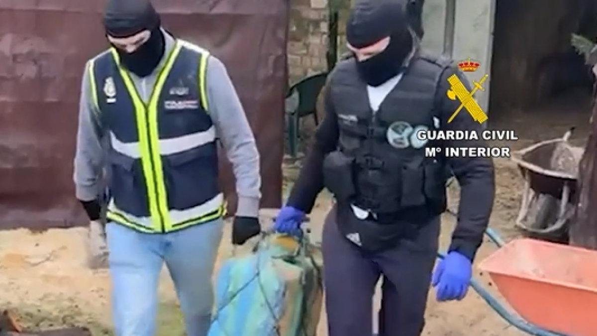 Un policía y un guardia civil transportan uno de fardos de droga.
