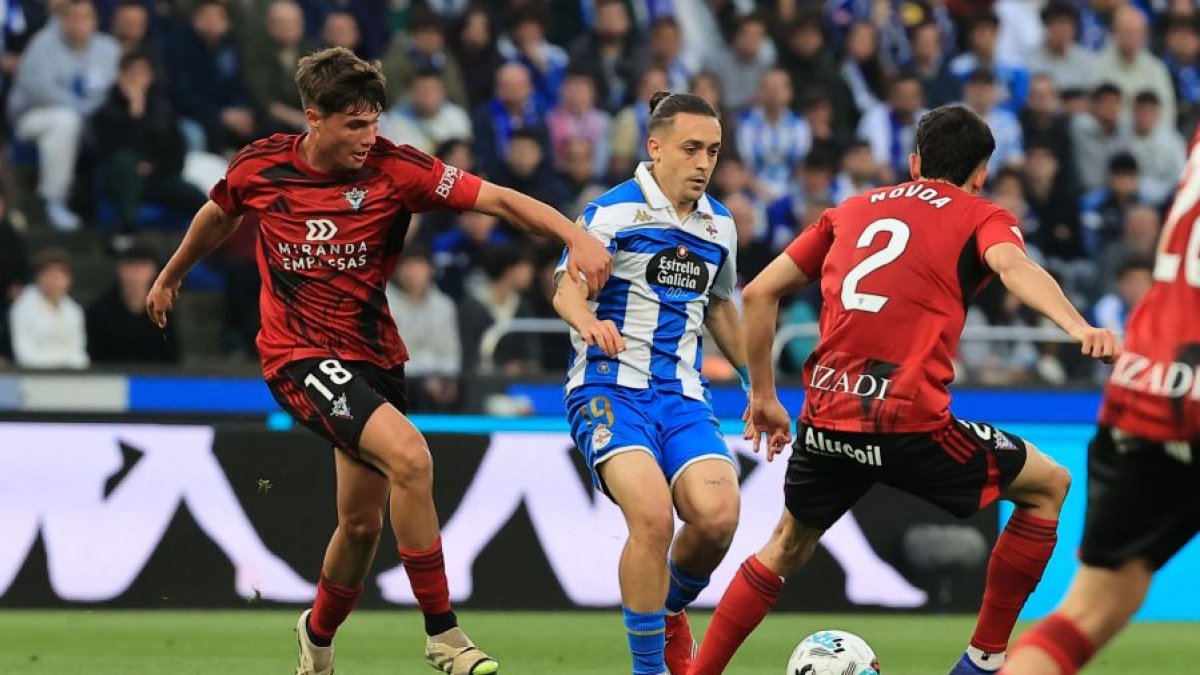 Los rojillos Bauza y Novoa intentan robar el balón al deportivista Luismi Cruz