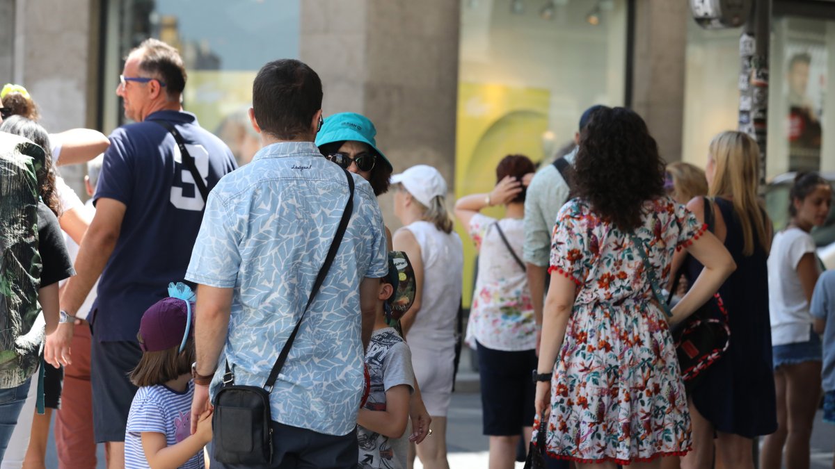 Archivo - Un grupo de gente espera a la sombra para cruzar un paso de peatones en la Gran Vía de Madrid.