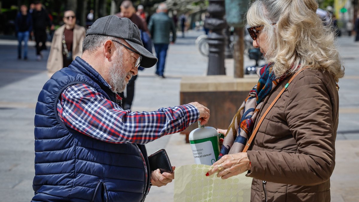 Un hombre colabora con la causa metiendo dinero en una hucha.