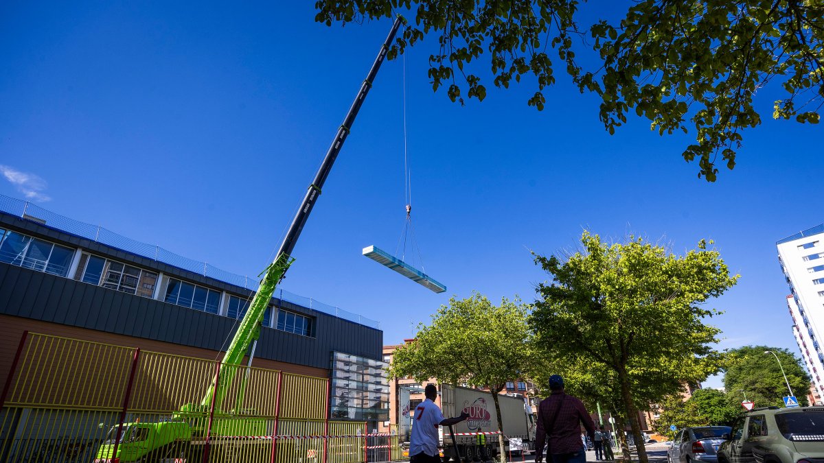 Una grúa descarga material para la obra de renovación de la cubierta del polideportivo Lavaderos.