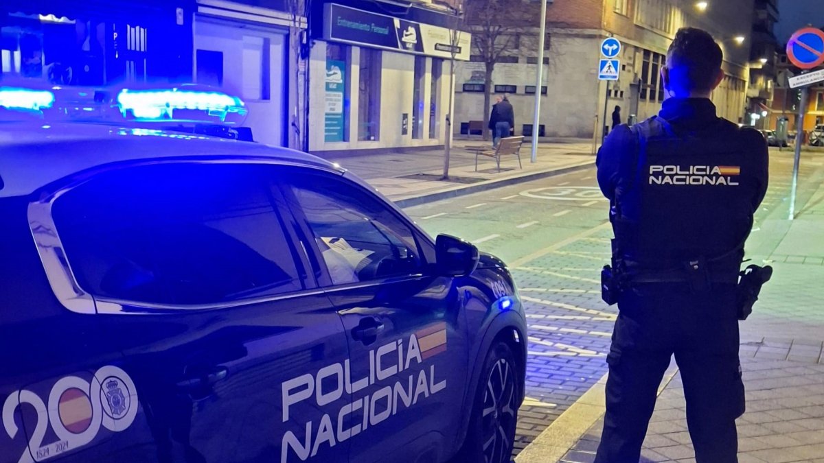 Un agente de policía junto a un coche patrulla.