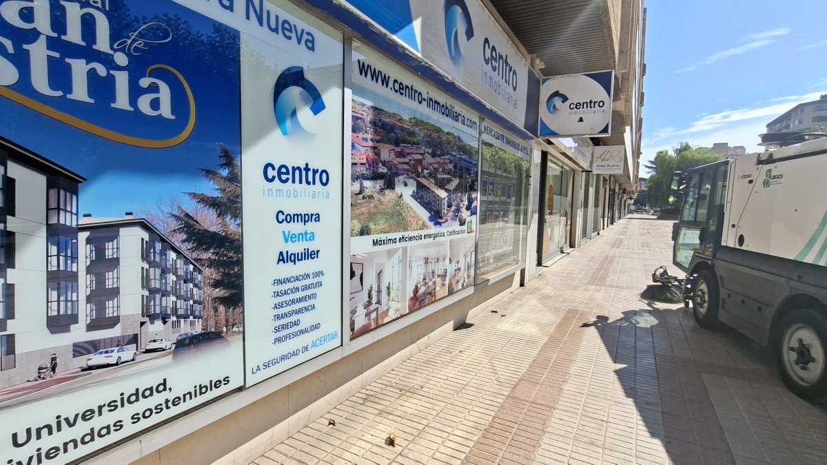Una máquina barredora pasa junto al escaparate de una inmobiliaria.