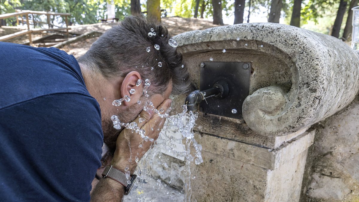 Un hombre se refresca en una fuente.