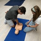 Dos personas practican una RCP a un maniquí en un curso de primeros auxilios.