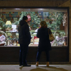 Dos personas observan el escaparate de una tienda de alimentación decorado ya con motivos navideños y artículos típicos de estas fiestas.-RAÚL G. OCHOA