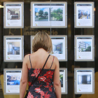 Una mujer observa anuncios de pisos en venta en el escaparate de una inmobiliaria. RAÚL G. OCHOA