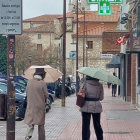 Dos mujeres se protegen de la lluvia con sendos paraguas, ayer en la calle Calzadas. L. G. L.