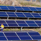 Un operario de Norsol inspecciona una batería de cuatro hileras de paneles solares junto a una balsa de riego agrícola.-ECB