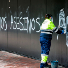 Un operario limpia las pintadas de 'asesinos' aparecidas el lunes en El Plantío.