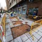 Varios peatones sortean las obras de cambio de baldosas en la calle Calzadas.