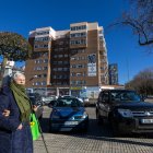 Dos mujeres pasan por la calle María Amigo, donde se puede ver la pancarta contra el aparcamiento.