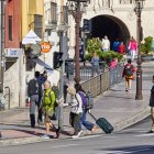 Turistas con maletas en la plaza de Vega, en las cercanías de la estación de autobuses y el Arco de Santa María y la Catedral.