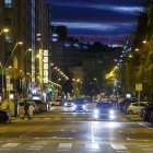Un peatón cruza la avenida Reyes Católicos de noche, ya con el alumbrado público encendido.