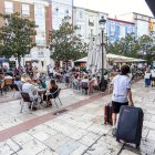Un joven arrastra sus maletas junto a una terraza del centro.
