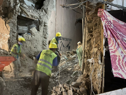Tres personas desescombran una zona derruida.