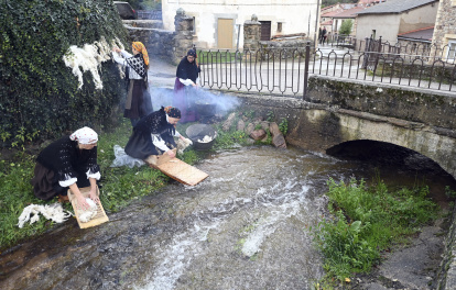 Un grupo de mujeres hace la colada en el río con la tabla de lavar.