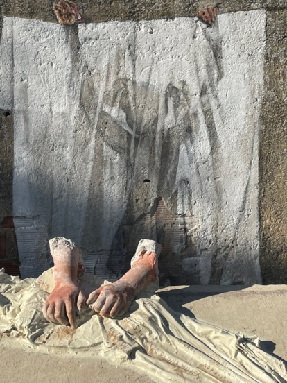 Dos manos lavan una tela cargada de mensajes machistas, en una intervención artística en Arroyal.s