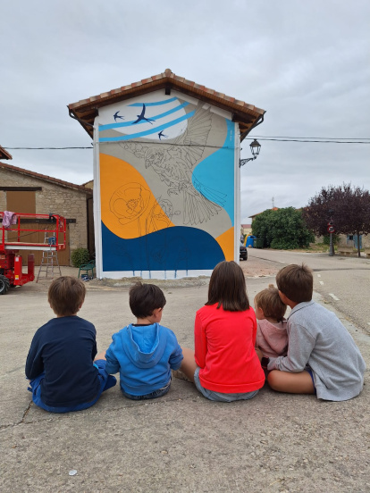 Varios niños del pueblo observan el mural durante el proceso de creación.